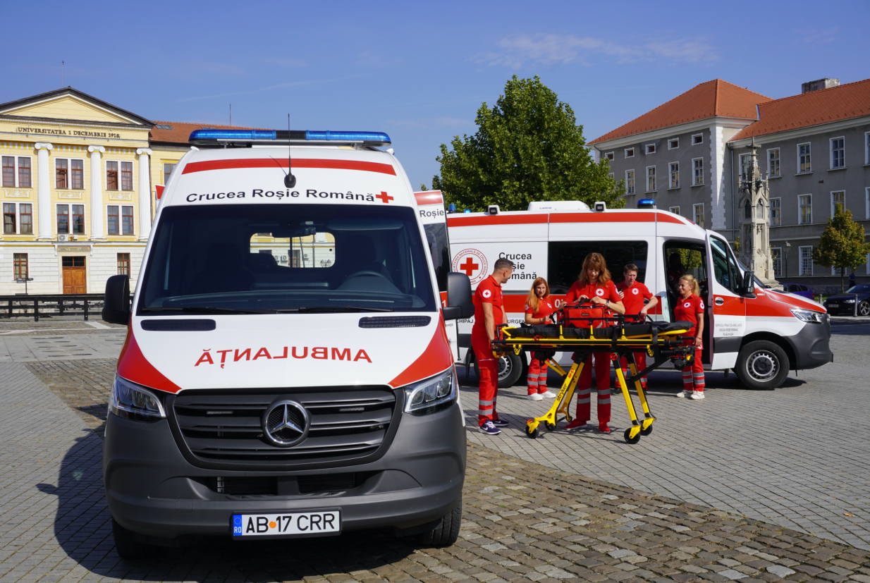 Voluntari și medici Crucea Roșie Alba lângă ambulanțe private
